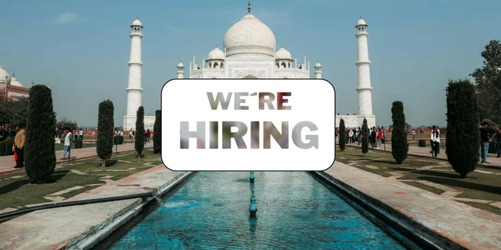 A sign that says "We're Hiring" in front of the Taj Mahal.
