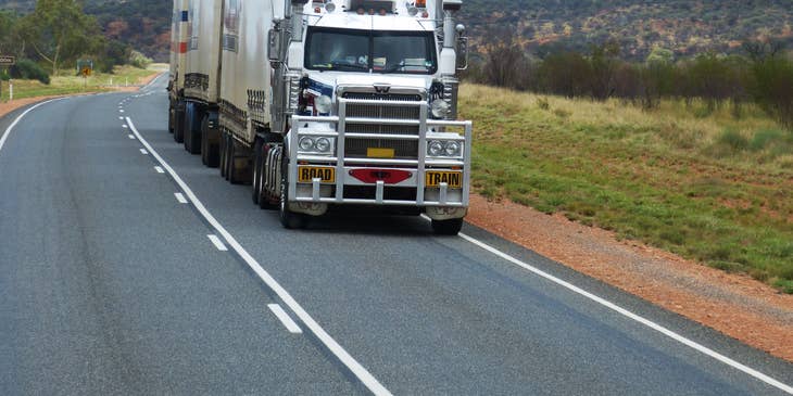 A truck driving on a road with green scenery.
