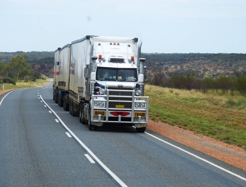 A truck driving on a road with green scenery.