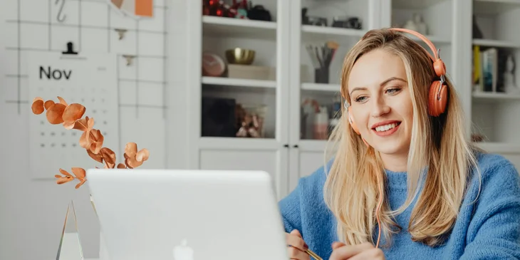 A freelancer happily writing a blog at home while listening to music.