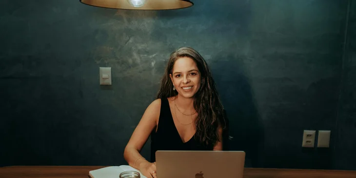 A woman sitting by a table with a pad and a laptop.