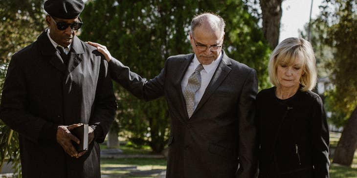 A funeral attendant comforting a grieving family.