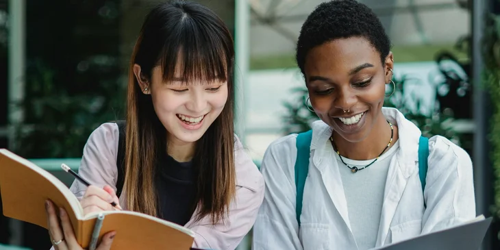 Two female friends studying together outdoors.