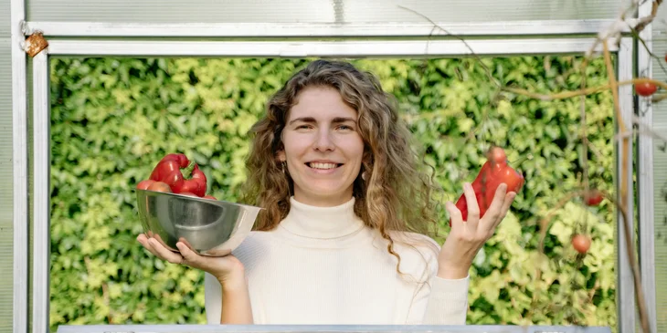 A woman holding red bell peppers.