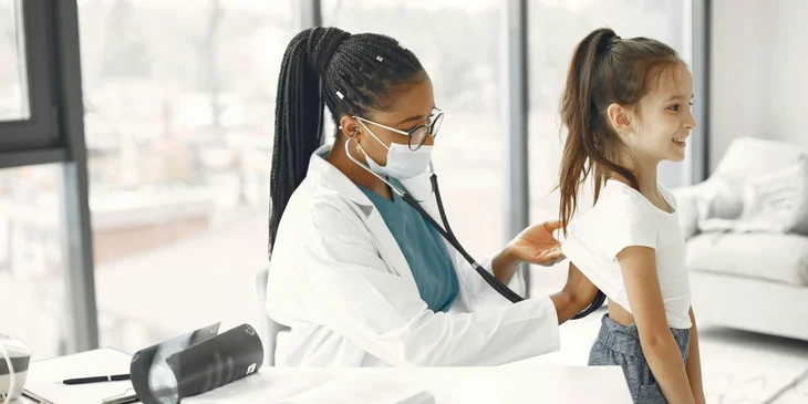 A doctor examining a young girl with a stethoscope.