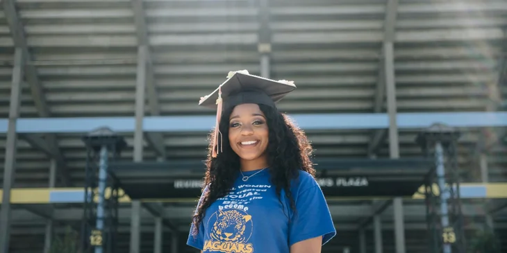 A female graduate student standing in a stadium.