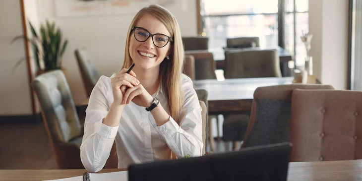 A woman smiling as she works at her desk.