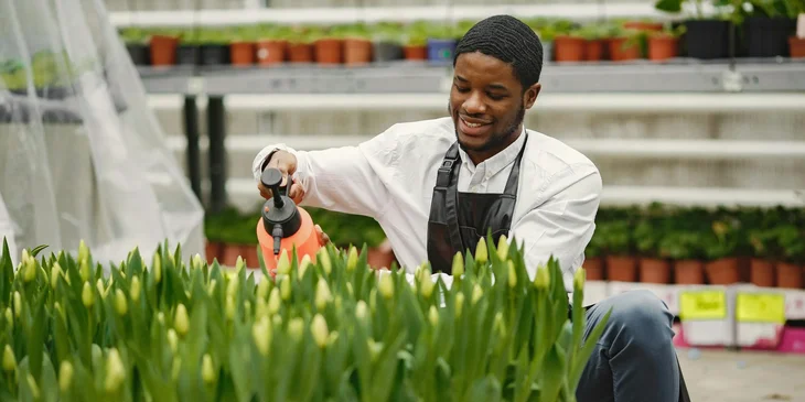 A man happily watering the plants.
