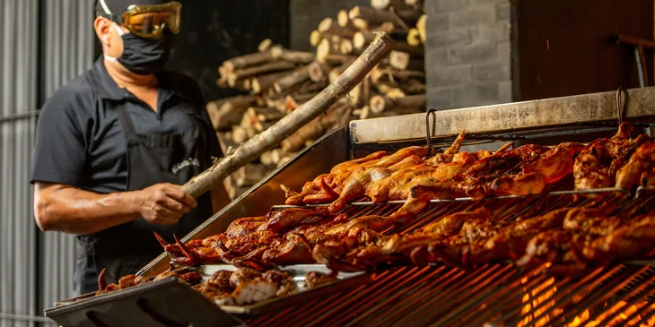 A grill cook roasting chicken on the barbecue.