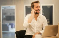 Un uomo seduto mentre parla con qualcuno al telefono.
