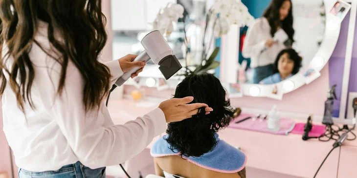 A hairstylist blow-drying a client's hair.