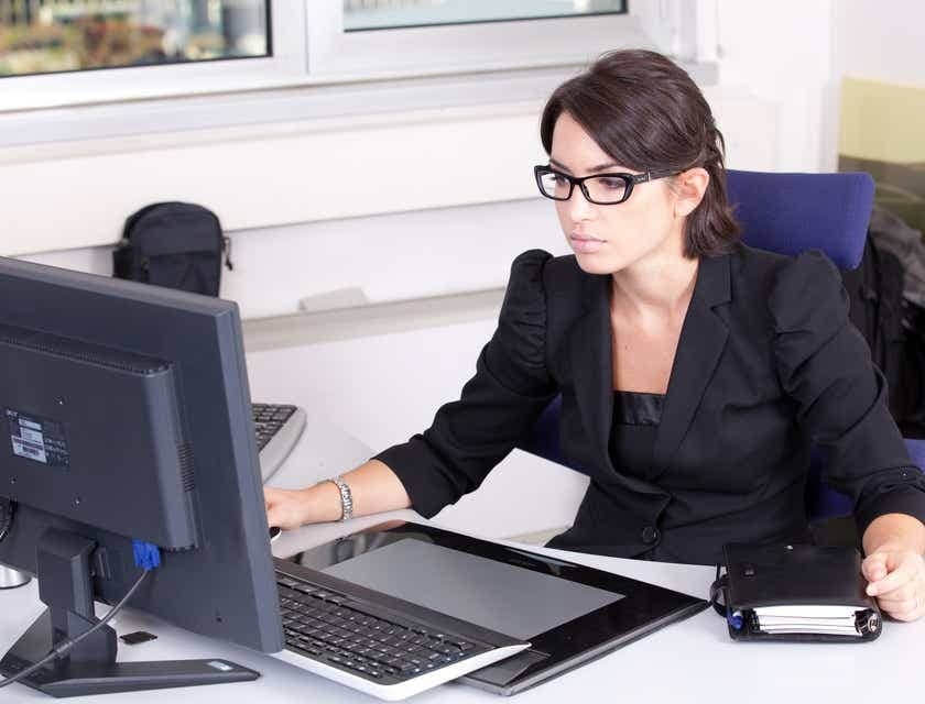 An accountant working with a laptop and diary on the desk.