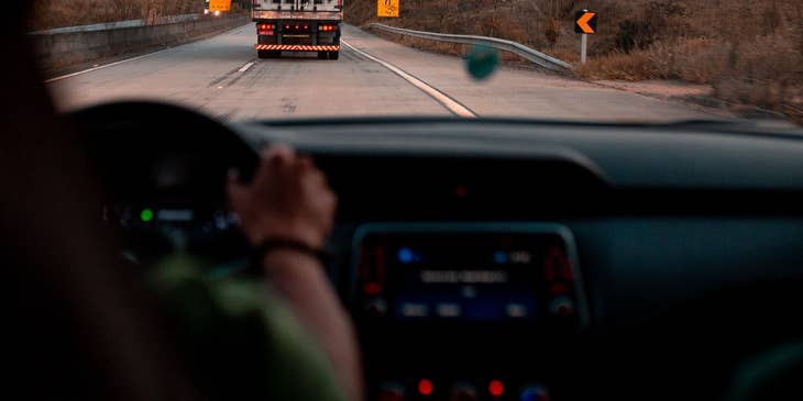 Truck driver holding steering wheel of truck.