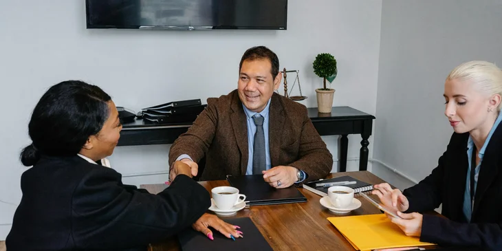 A Hispanic man shakes hands with a coworker after the meeting.