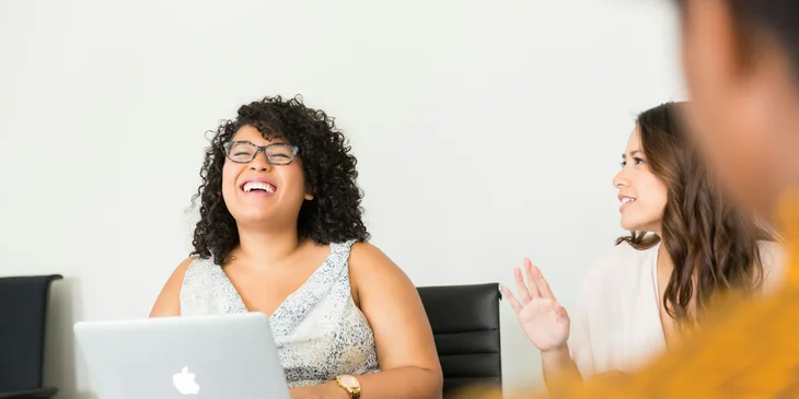 A woman smiling during a conversation with her coworkers.