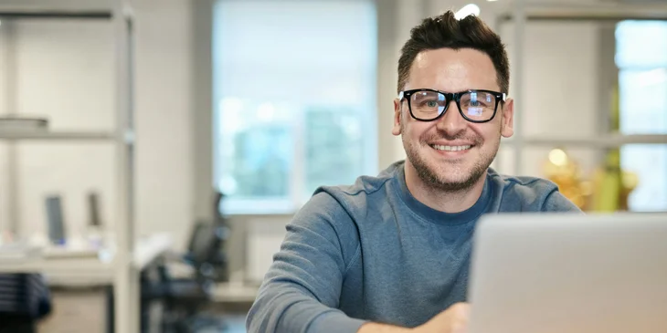 A man smiling as he works at his computer.