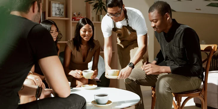 A waiter serves coffee on a table.