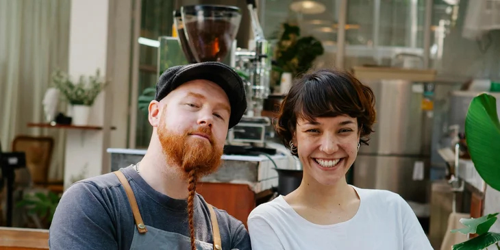 Two hospitality workers smiling.
