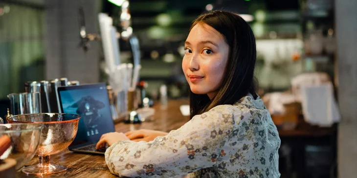 A cheerful young woman typing on a laptop.