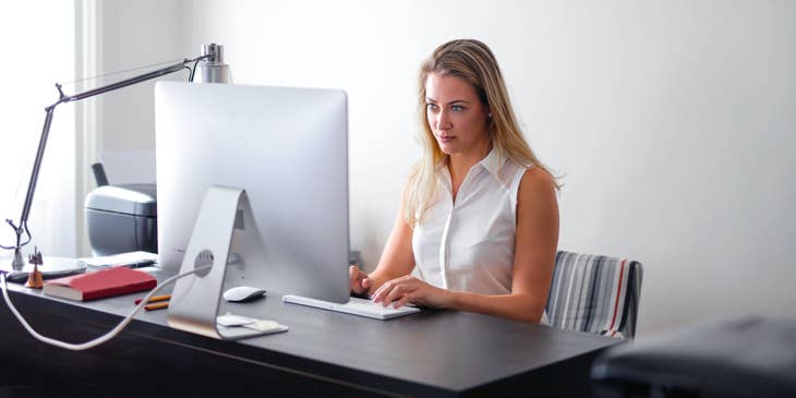A woman performing employee background checks on a laptop.