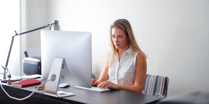 A woman performing employee background checks on a laptop.