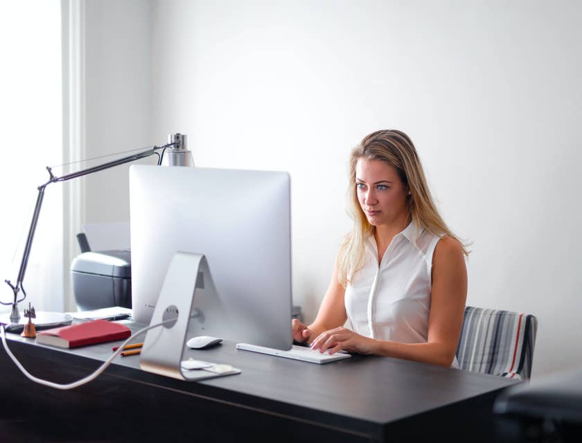 A woman performing employee background checks on a laptop.