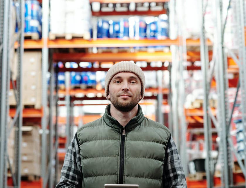 A retail manager standing in a warehouse while holding a tablet.