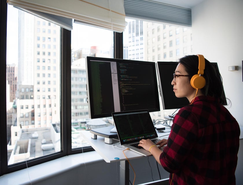 software engineer with orange headphones working in front of multiple monitors