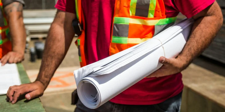 A construction worker holding plans.