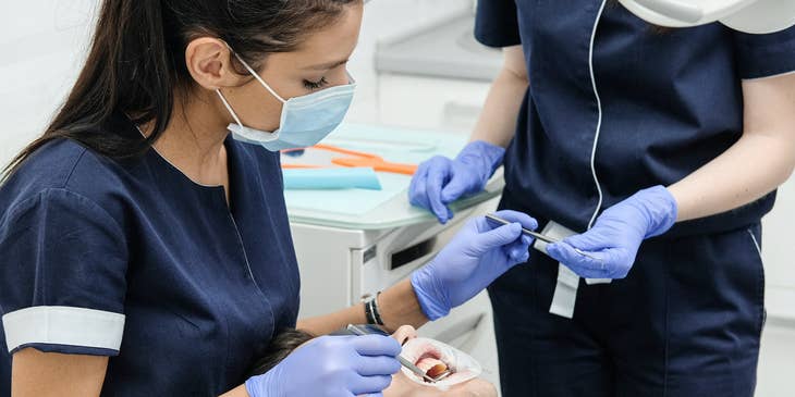 dentist and dental assistant cleaning teeth