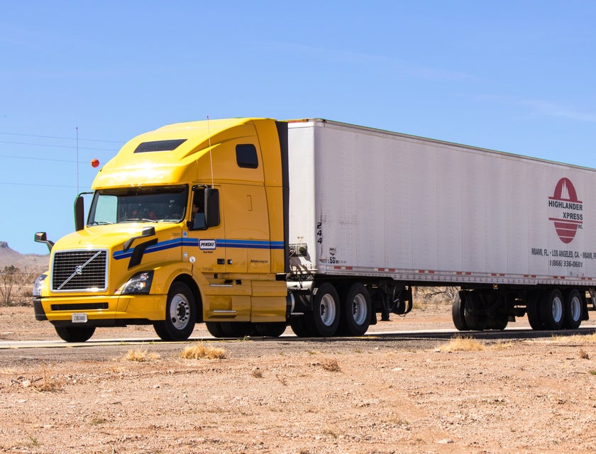 A yellow and white lorry on the road.