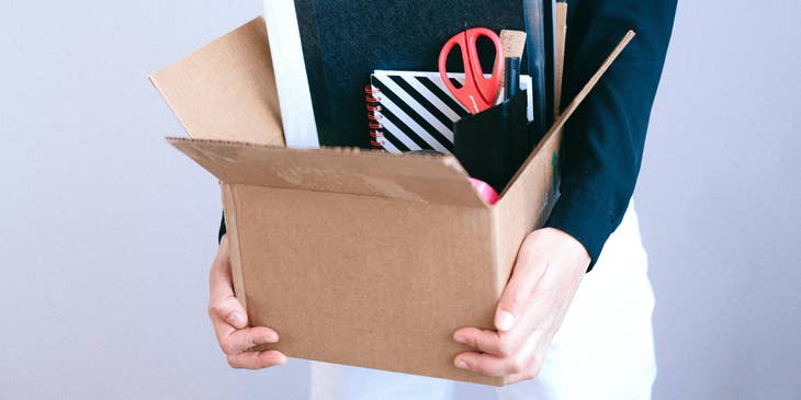 Employee who has been fired holding a box containing their belongings.