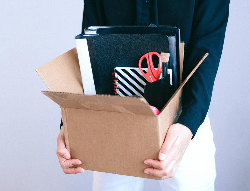 Employee who has been fired holding a box containing their belongings.