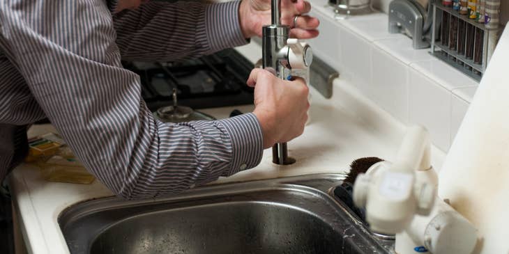 Plumber working on the plumbing in the kitchen.