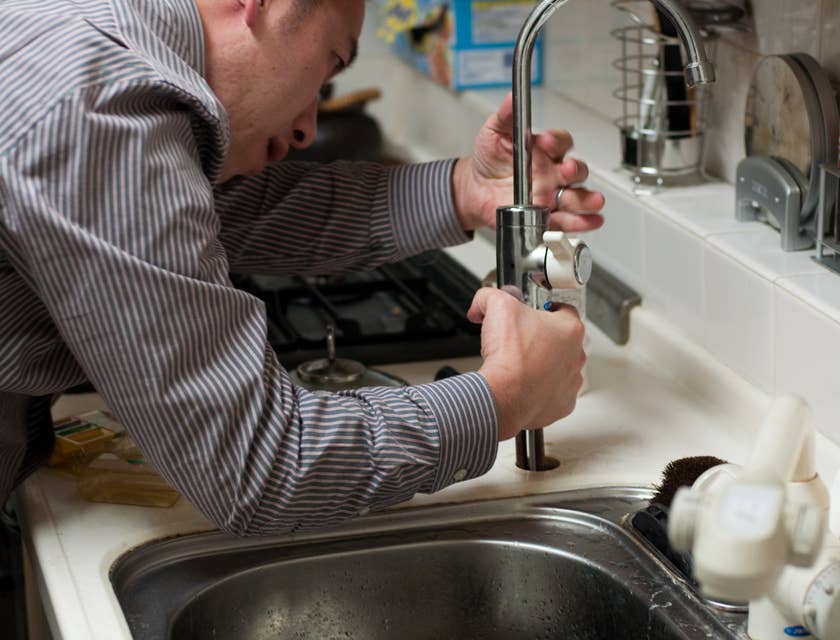 Plumber working on the plumbing in the kitchen.