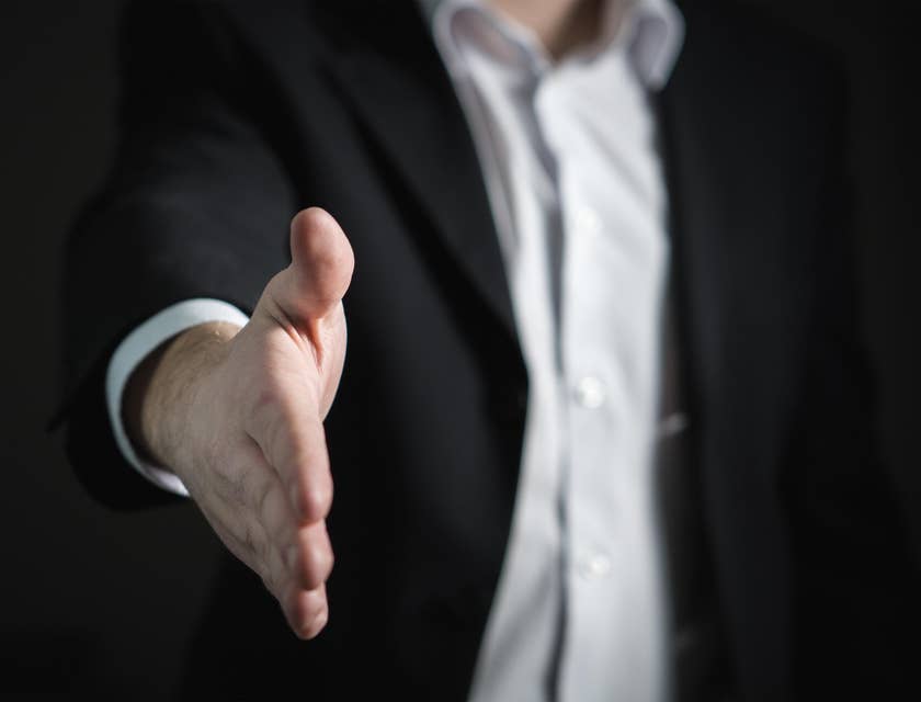 A man making a job offer and extending a hand to shake.