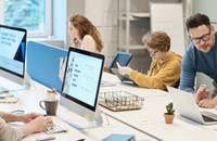 Grupo de personas sentadas alrededor de una mesa, con dos personas dándose la mano.