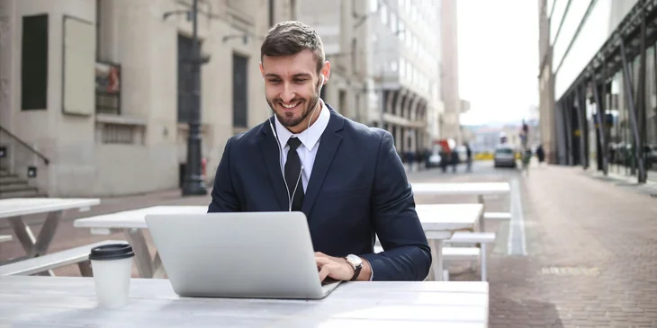 A man in black suit jacket using a laptop.