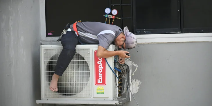 An HVAC technician fixing an air conditioner.