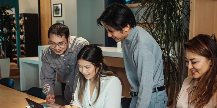 A woman shows her coworkers documents on her laptop.