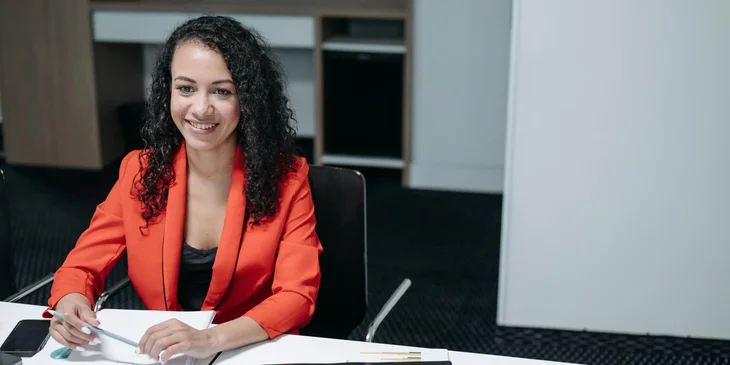 A woman smiling while working at her desk.