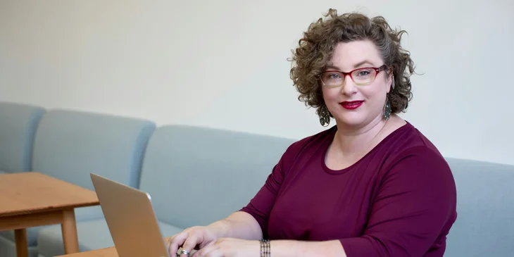 A smiling woman working on her laptop.