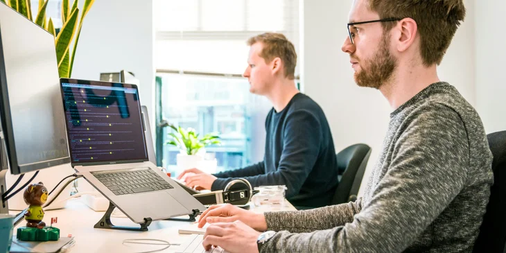 Two coworkers working on their laptops.