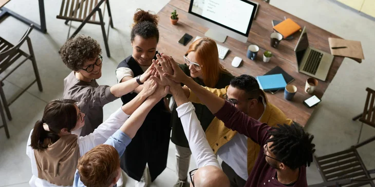 Funcionários guiados por princípios de liderança inclusiva unindo as mãos.