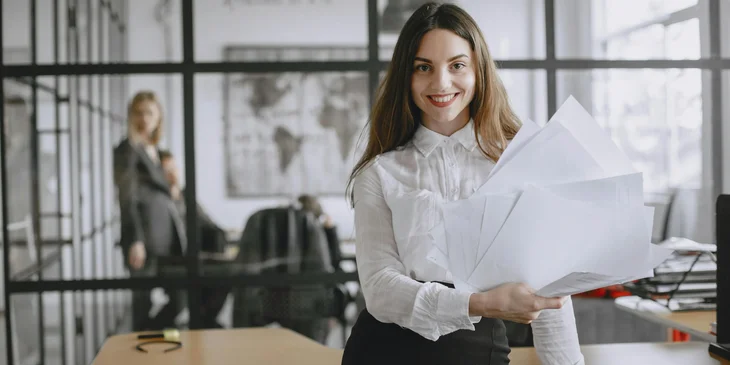 A woman holding papers in an office.