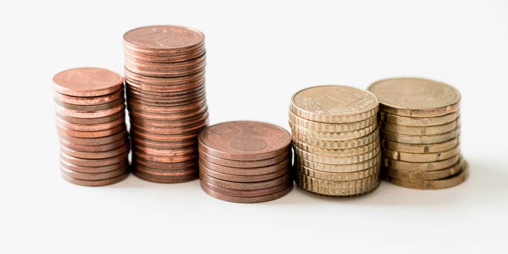 Cinco pilas de monedas de oro sobre un fondo blanco.