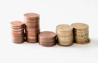 Cinco pilas de monedas de oro sobre un fondo blanco.