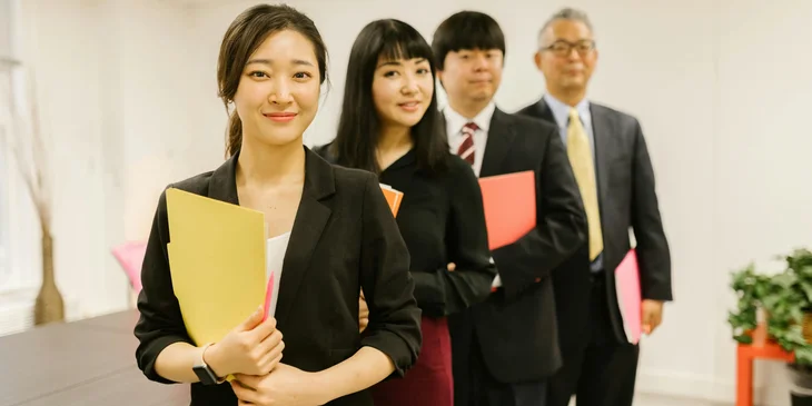 A woman posing with her coworkers at an office.
