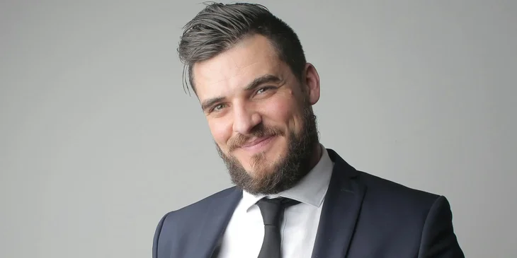 A man in black suit smiling at the camera.