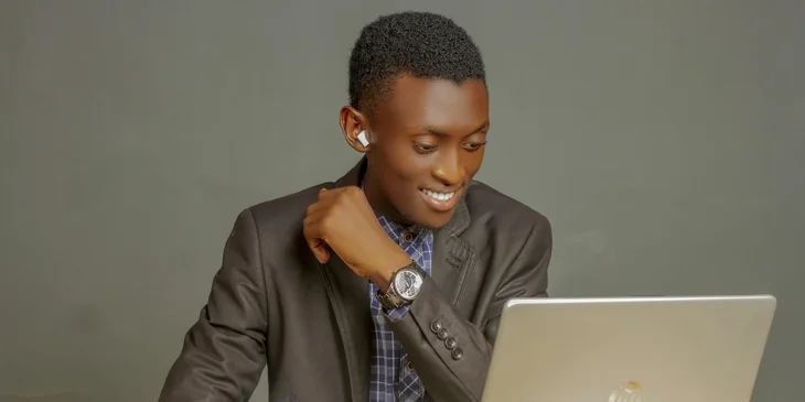 A man in a gray suit jacket using a laptop.